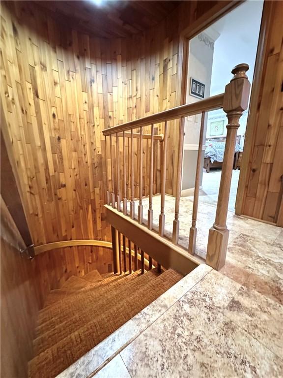 stairway featuring wooden walls