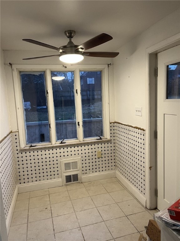 tiled spare room with ceiling fan and tile walls