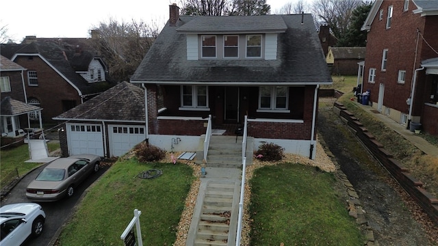 view of front property with covered porch, a garage, and a front yard