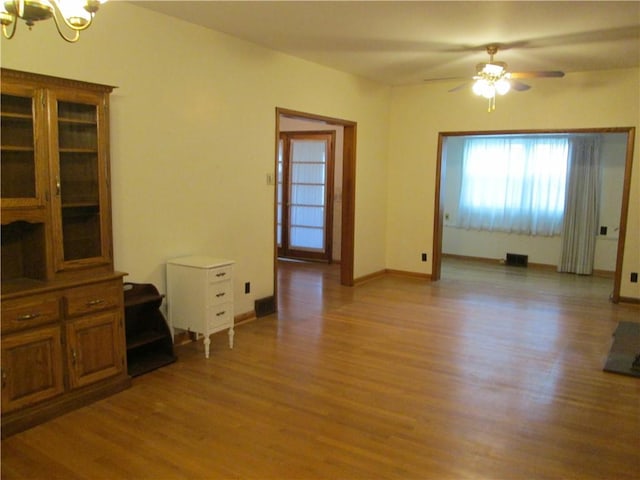 interior space with ceiling fan with notable chandelier and light wood-type flooring