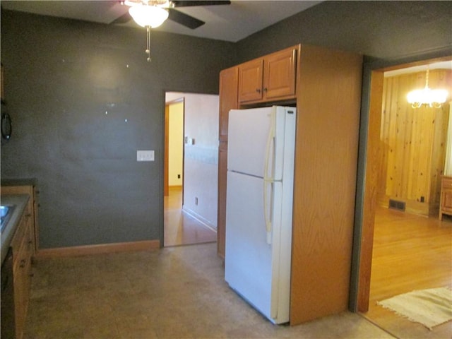 kitchen with ceiling fan with notable chandelier and white fridge