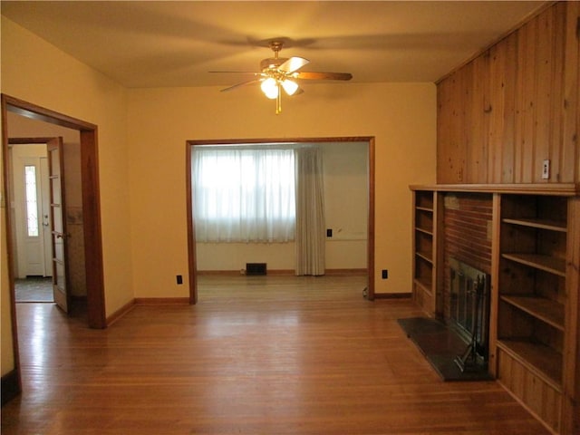 unfurnished living room with hardwood / wood-style flooring, ceiling fan, and a fireplace