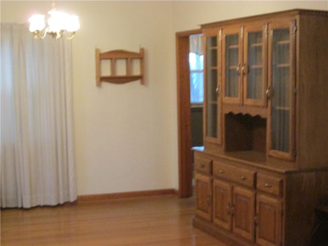 hallway with a chandelier and light hardwood / wood-style floors