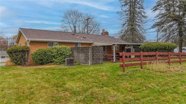 rear view of house with a lawn and central air condition unit