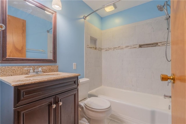 full bathroom featuring vanity, tiled shower / bath combo, and toilet