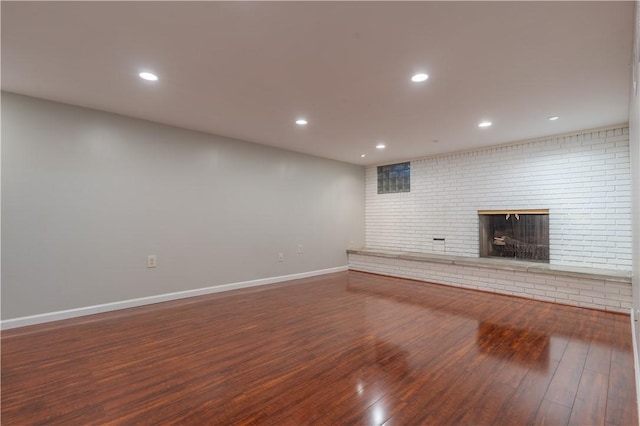 unfurnished living room with a fireplace, hardwood / wood-style floors, and brick wall