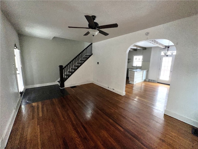 unfurnished living room featuring a textured ceiling, wood-type flooring, and ceiling fan with notable chandelier