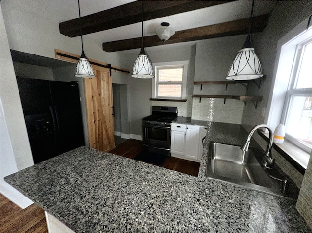 kitchen with beamed ceiling, a barn door, black refrigerator, and stainless steel gas range