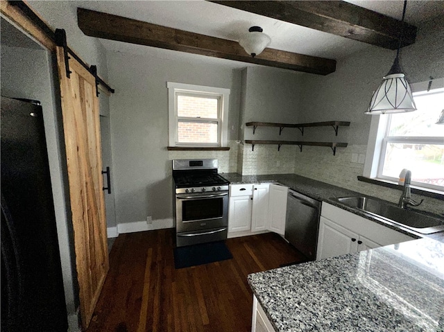 kitchen featuring hanging light fixtures, sink, a barn door, appliances with stainless steel finishes, and white cabinetry