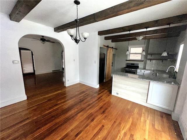 kitchen with sink, hanging light fixtures, dark hardwood / wood-style floors, a barn door, and gas stove