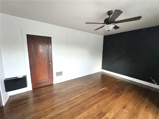 unfurnished room featuring dark hardwood / wood-style floors, ceiling fan, and heating unit