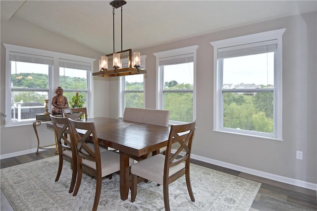 dining space with a notable chandelier, wood-type flooring, and vaulted ceiling