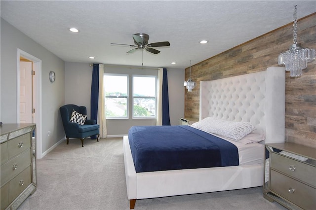 carpeted bedroom featuring a textured ceiling, wood walls, and ceiling fan with notable chandelier