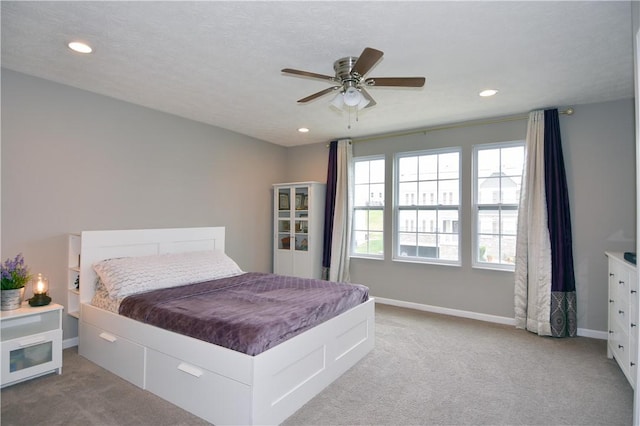 bedroom featuring ceiling fan, light colored carpet, and a textured ceiling