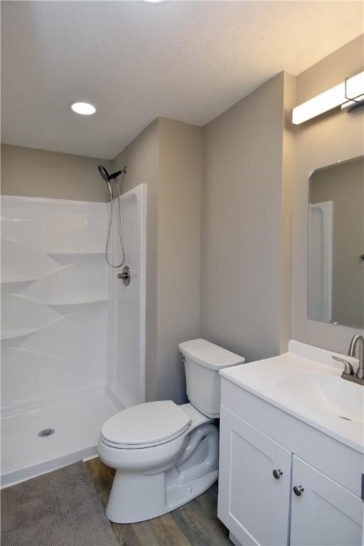 bathroom featuring walk in shower, vanity, a textured ceiling, wood-type flooring, and toilet