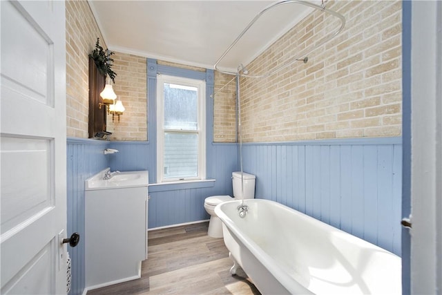 bathroom featuring crown molding, wood-type flooring, toilet, wooden walls, and vanity