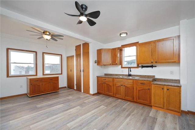 kitchen featuring ceiling fan, sink, a healthy amount of sunlight, and light hardwood / wood-style flooring