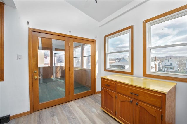 doorway with light hardwood / wood-style flooring and vaulted ceiling