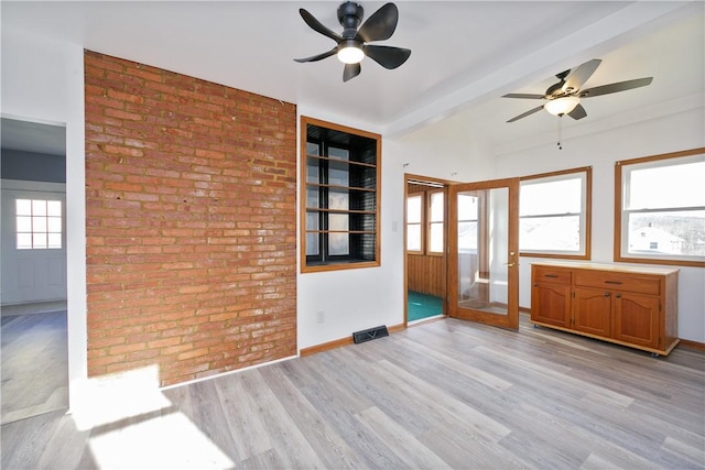 spare room with beamed ceiling, plenty of natural light, light hardwood / wood-style floors, and ceiling fan