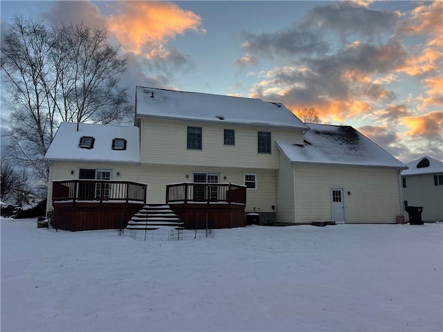 snow covered house with a wooden deck