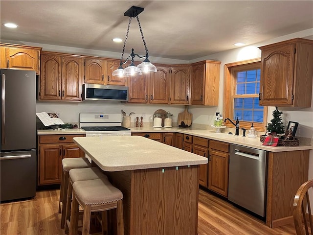 kitchen with light countertops, light wood-style flooring, brown cabinetry, and stainless steel appliances