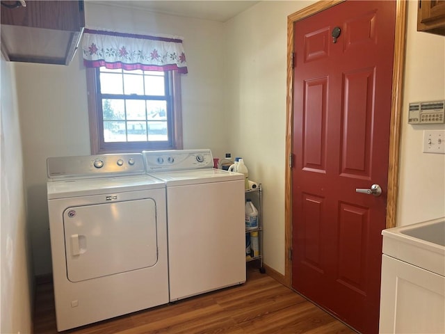 clothes washing area with cabinets, wood-type flooring, and separate washer and dryer