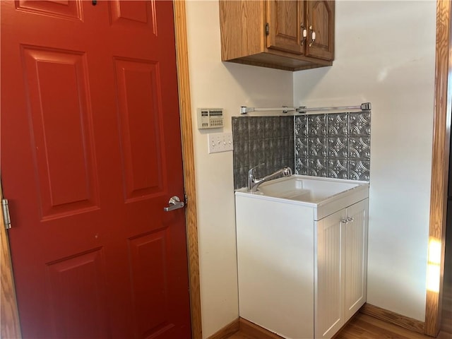 laundry area with baseboards, a sink, and wood finished floors