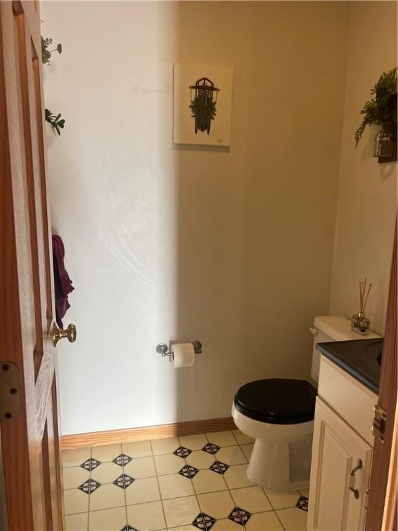 bathroom featuring toilet, vanity, and baseboards
