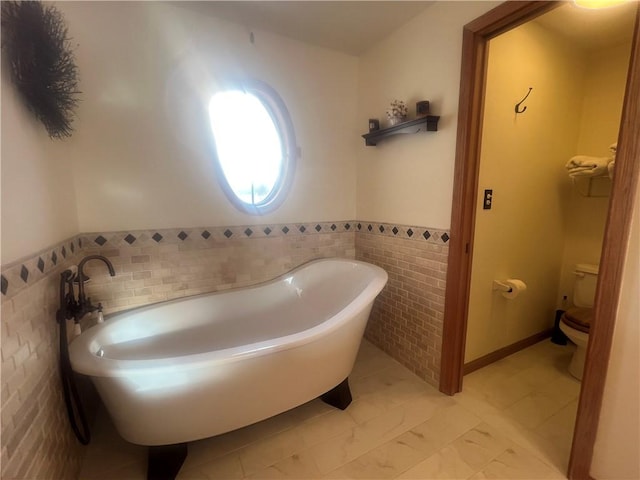 bathroom with a bath, toilet, and tile walls