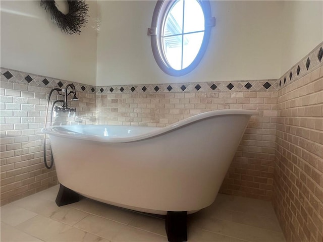 bathroom featuring tile walls, wainscoting, and a freestanding bath