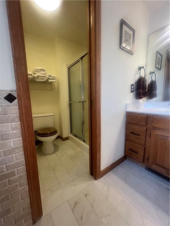 bathroom with a shower stall, baseboards, marble finish floor, toilet, and vanity