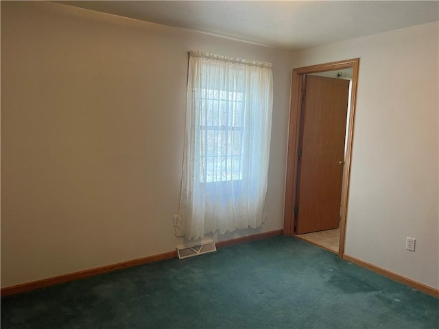 empty room with baseboards, visible vents, and carpet floors