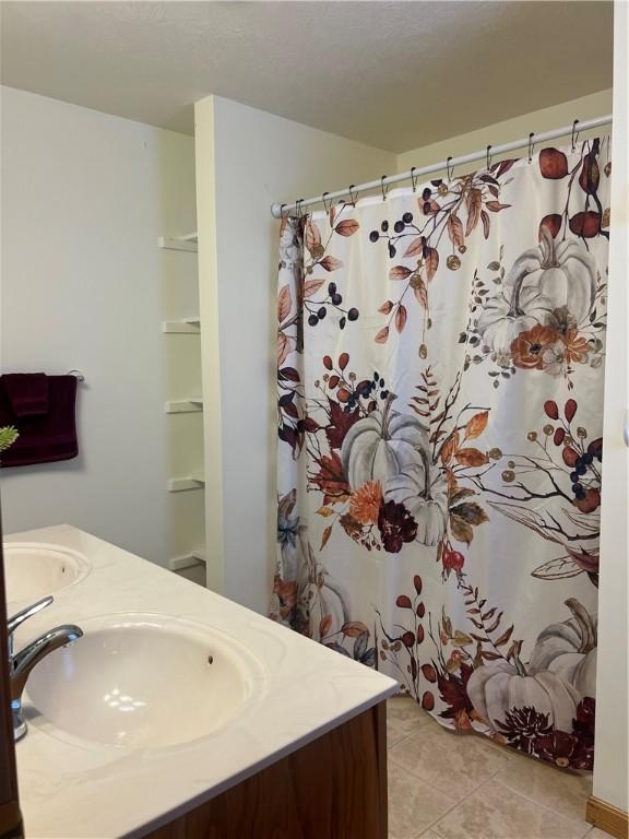 bathroom featuring double vanity, a shower with shower curtain, a sink, and tile patterned flooring