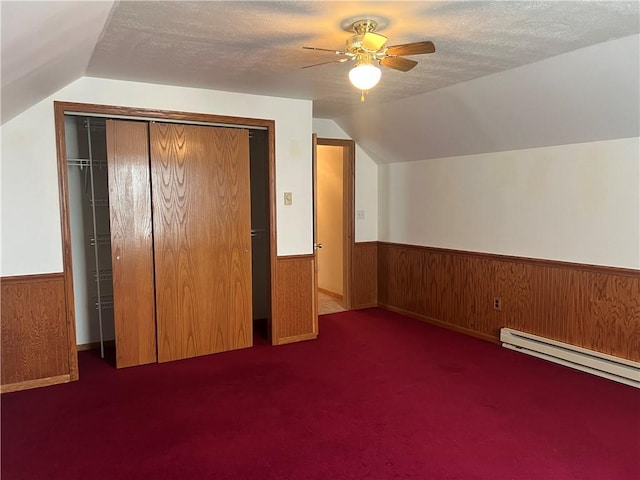 additional living space with a textured ceiling, ceiling fan, vaulted ceiling, and dark colored carpet