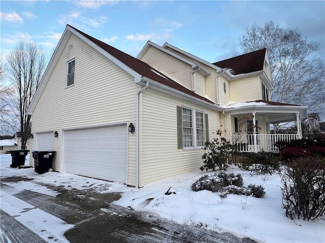 view of snow covered exterior featuring a garage and covered porch