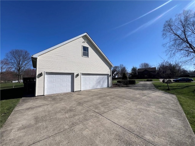 view of side of property featuring driveway, a garage, and a yard