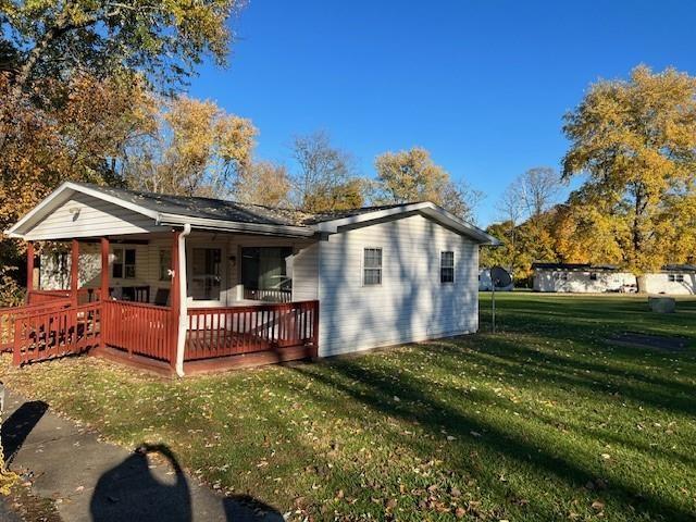 back of property with a lawn, covered porch, and a deck