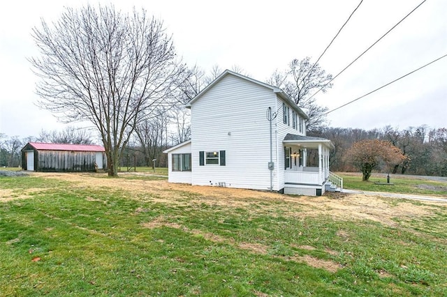 view of side of property featuring a yard, an outbuilding, and covered porch