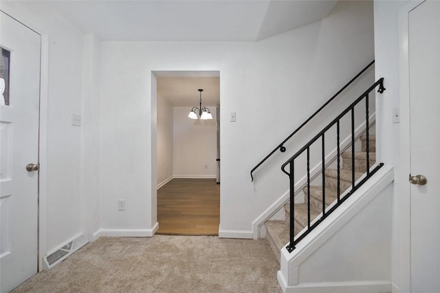 stairway featuring carpet flooring and an inviting chandelier