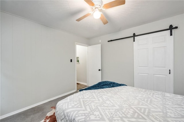 carpeted bedroom featuring ceiling fan and a barn door