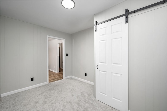 unfurnished bedroom featuring a barn door, light colored carpet, and a closet