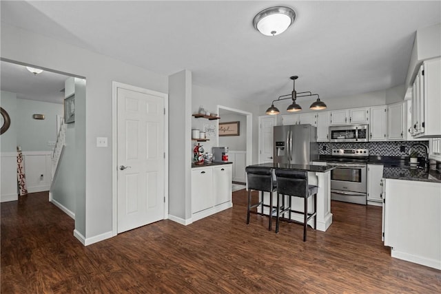 kitchen featuring dark hardwood / wood-style floors, a kitchen island, a kitchen bar, and appliances with stainless steel finishes