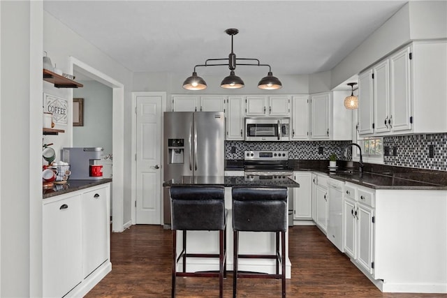 kitchen with a center island, dark wood-type flooring, white cabinets, sink, and appliances with stainless steel finishes