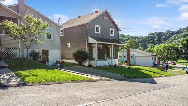 view of front of house featuring an outdoor structure, covered porch, a front yard, and a garage