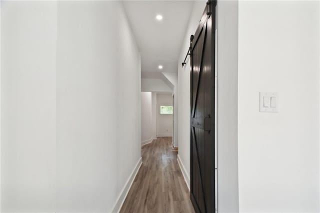 hall with a barn door and hardwood / wood-style flooring