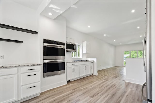 kitchen with light stone counters, white cabinets, light hardwood / wood-style floors, and appliances with stainless steel finishes