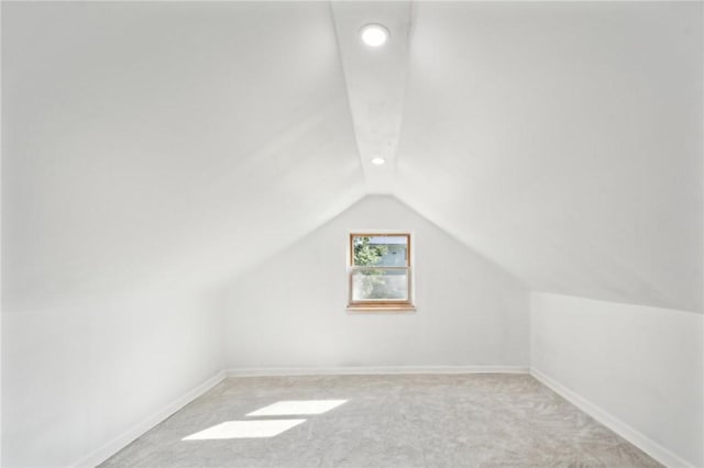 additional living space with light colored carpet and vaulted ceiling