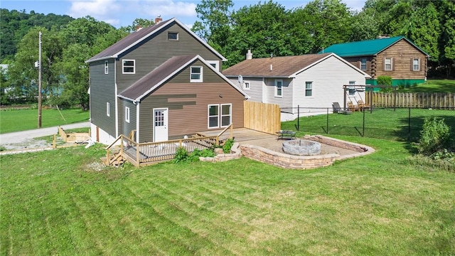 back of property featuring a lawn, a wooden deck, and a fire pit