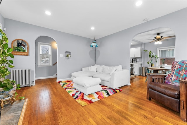 living room featuring ceiling fan, radiator heating unit, and light wood-type flooring