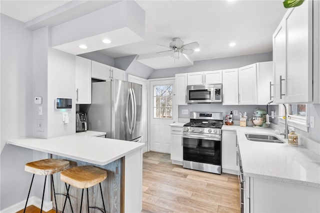 kitchen featuring sink, a breakfast bar area, light wood-type flooring, white cabinetry, and stainless steel appliances